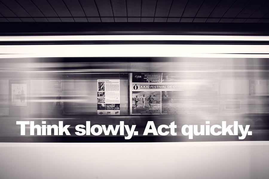 Traing speeding past platform with 'Think Slowly. Act Quickly.' quote